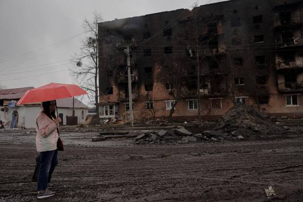 A woman stands in front of a burned out residential building after Ukrainian forces expelled Russian troops from the town of Trostyanets which Russia occupied at the beginning of its war with Ukraine