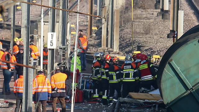 Rescuers stand next the wreckage of a passenger and freight train after a crash near Bettembourg