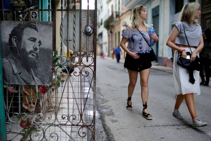 Tourists walk past an image of Cuba's late president Fidel Castro in downtown Havana