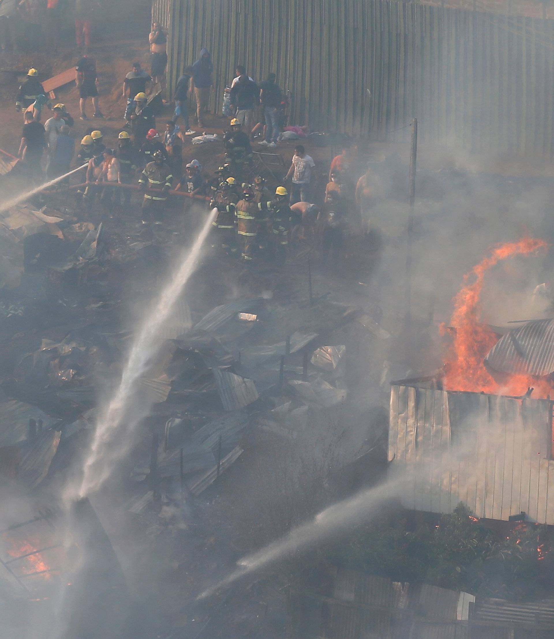 Firefighters work to put out a fire in a house on a hill, where more than 100 homes were burned due to a forest fire but there have been no reports of death, local authorities said in Valparaiso, Chile