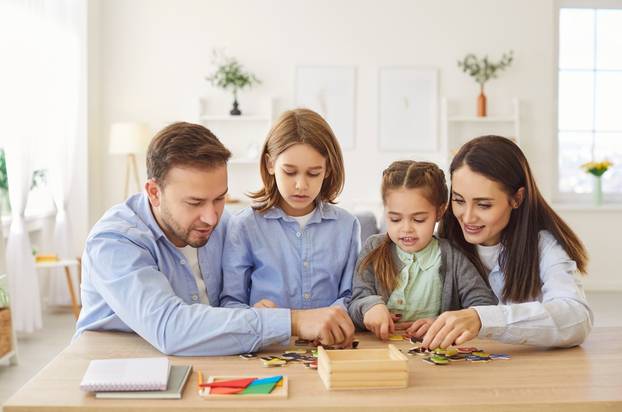 Happy,Young,Family,Sitting,At,Table,And,Playing,Developing,Educational