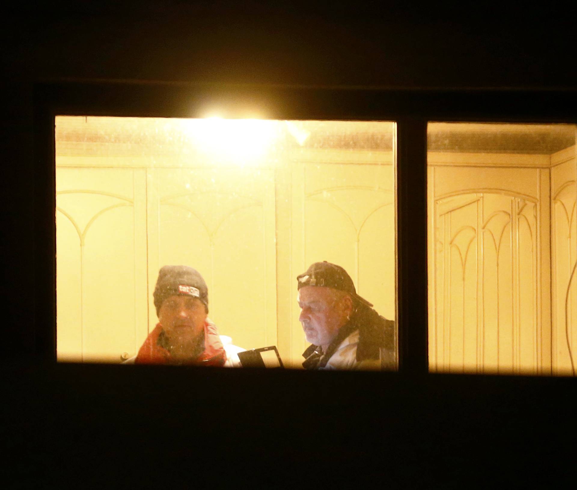 Crime scene investigators are seen through the window of a house where six people were found dead in Boeheimkirchen