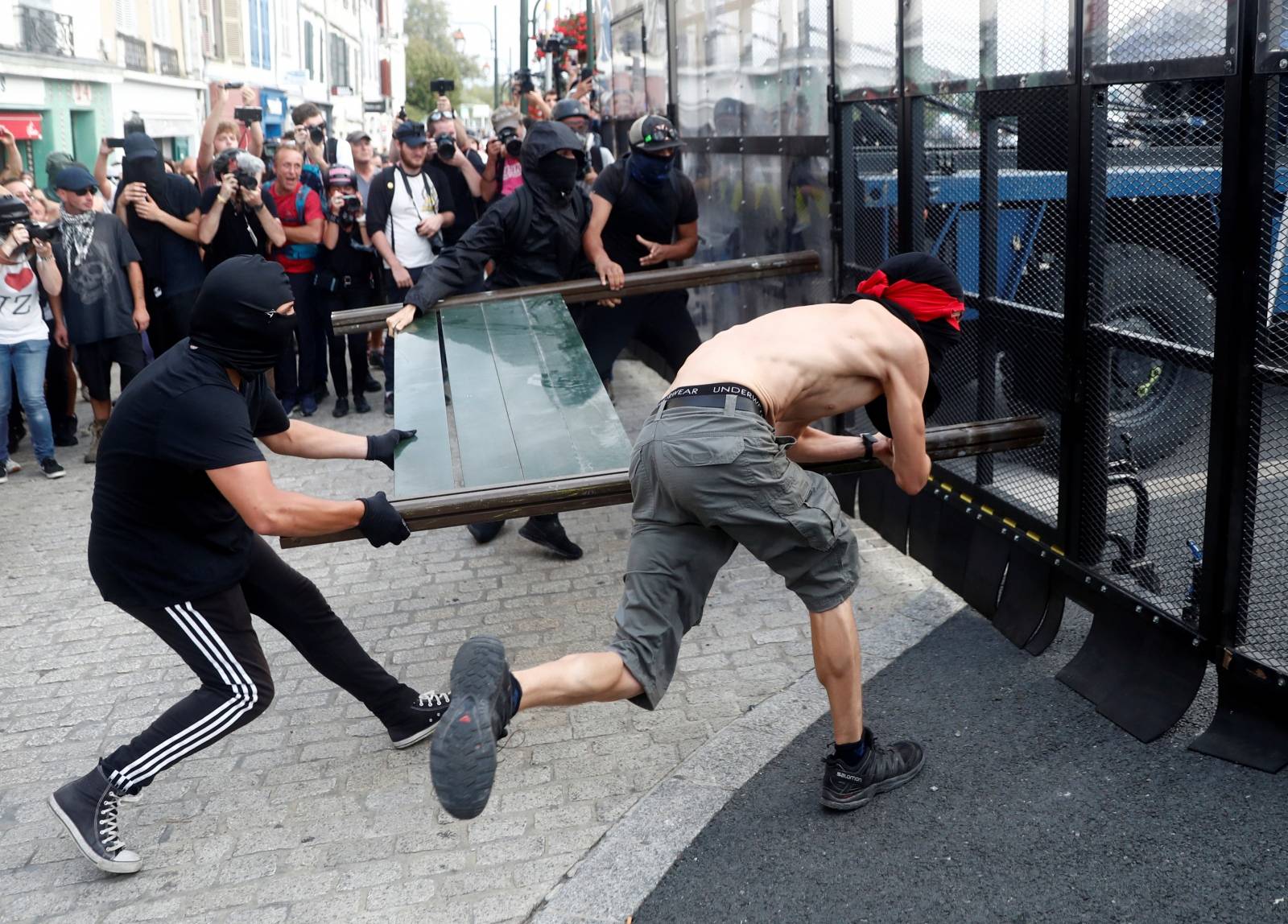 Demonstrators use a part of a barricade to attack the police blockade during a protest against G7 summit, in Bayonne