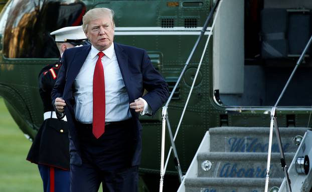 U.S. President Donald Trump adjusts his jacket as he walks from Marine One upon his return to the White House in Washington