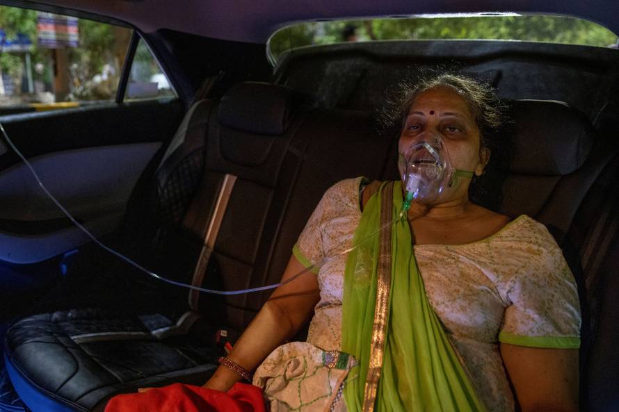 A woman with a breathing problem receives oxygen support for free inside her car at a Gurudwara, in Ghaziabad