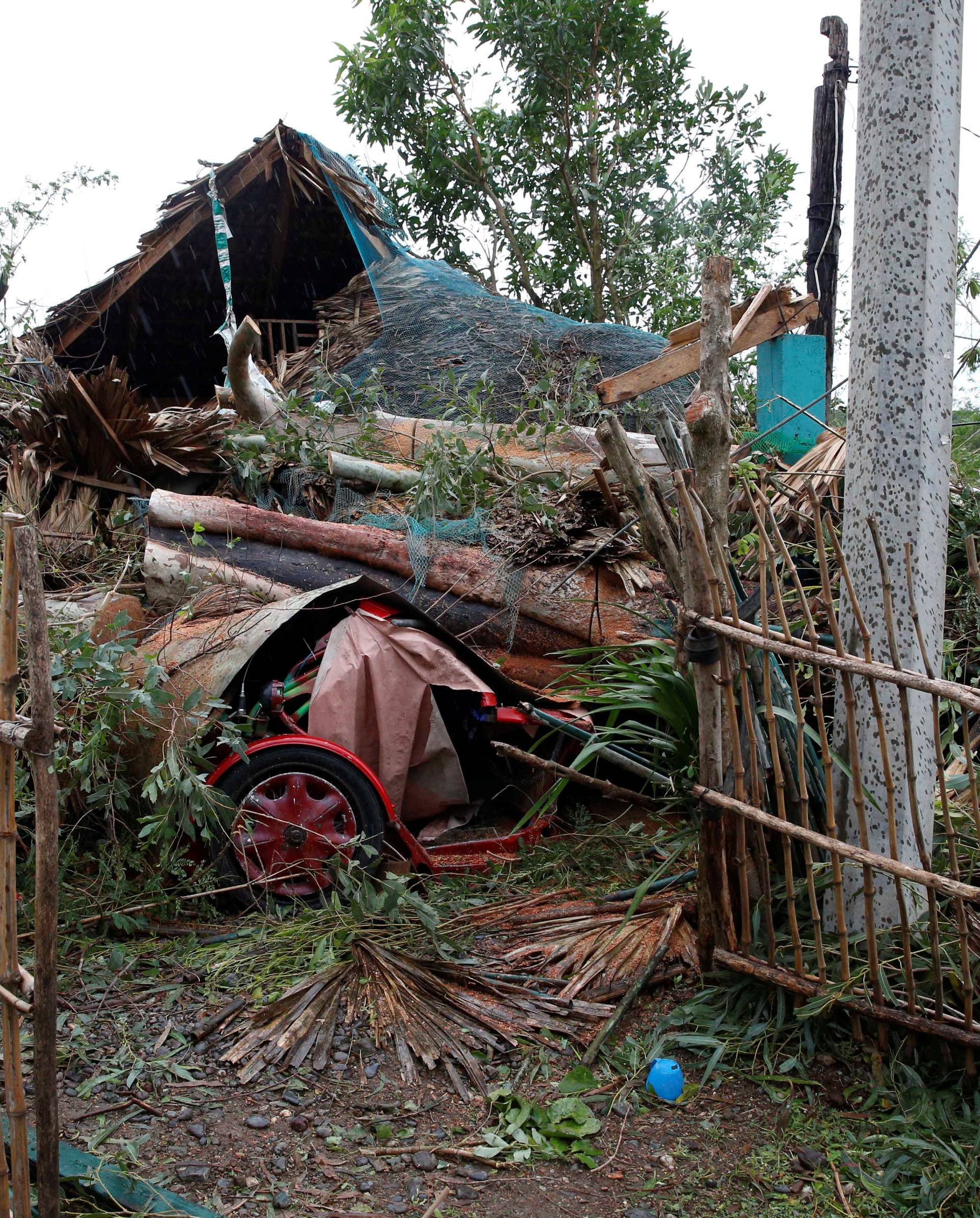 A woman stands outside her house which was damaged by a fallen tree during Typhoon Haima, in Bangui, Ilocos Norte