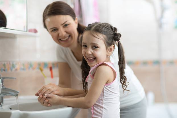 kid with mom washing her hands in bathroom