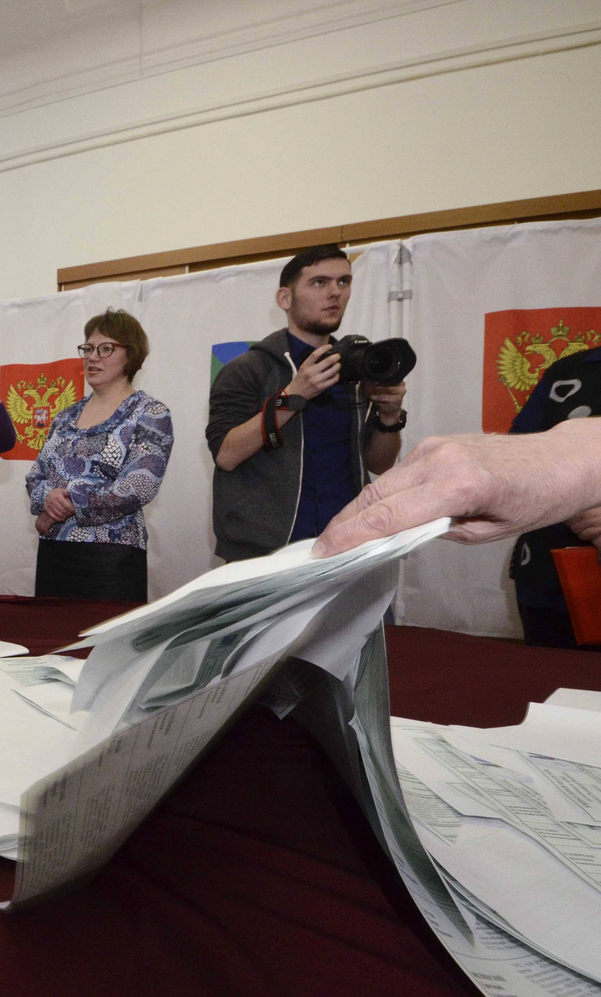 Members of a local election commission empty a ballot box before starting to count votes during the presidential election in Vladivostok