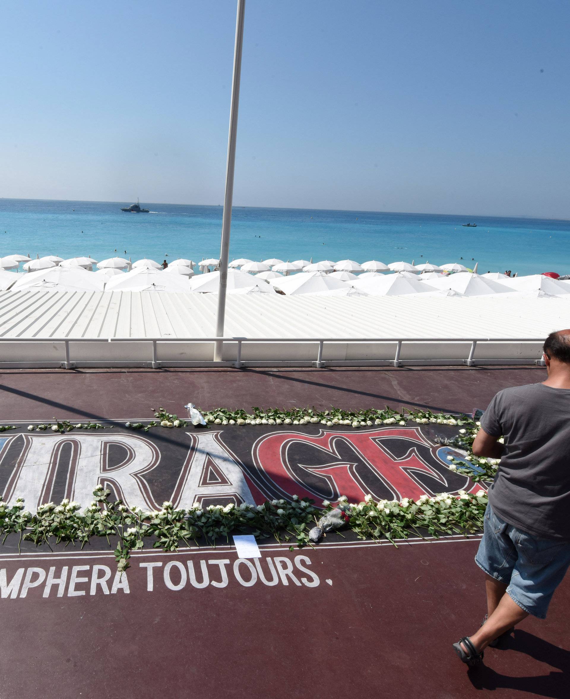 Tourists walk along the Promenade des Anglais as part of the commemorations of last year's July 14 fatal truck attack on the Promenade des Anglais in Nice