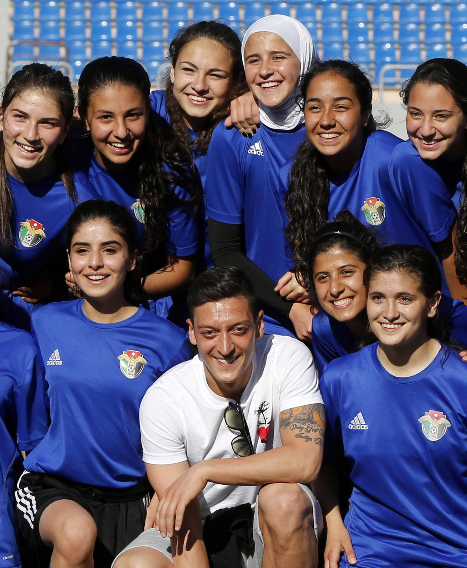 Germany and Arsenal player Mesut Ozil poses with the Jordanian U-17 women's national soccer team, as he attends the team training at Amman International Stadium in Amman