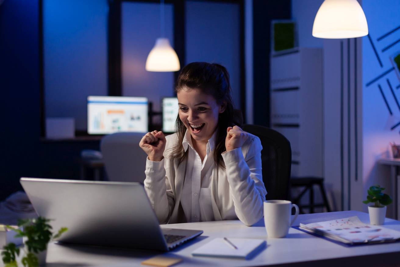 Happy businesswoman reading great online news on laptop