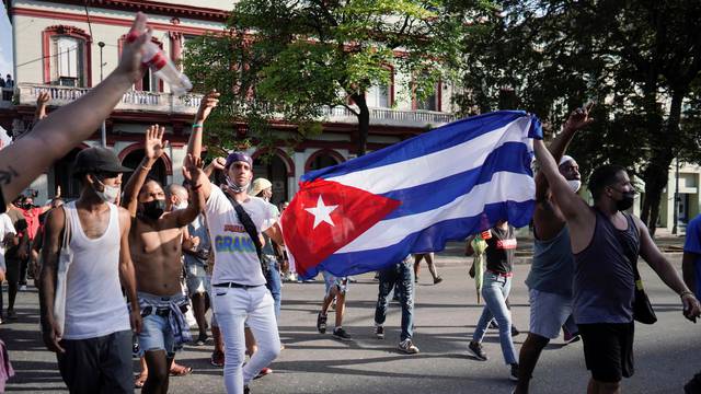 People hold Cuba's national flag during protests against and in support of the government, in Havana