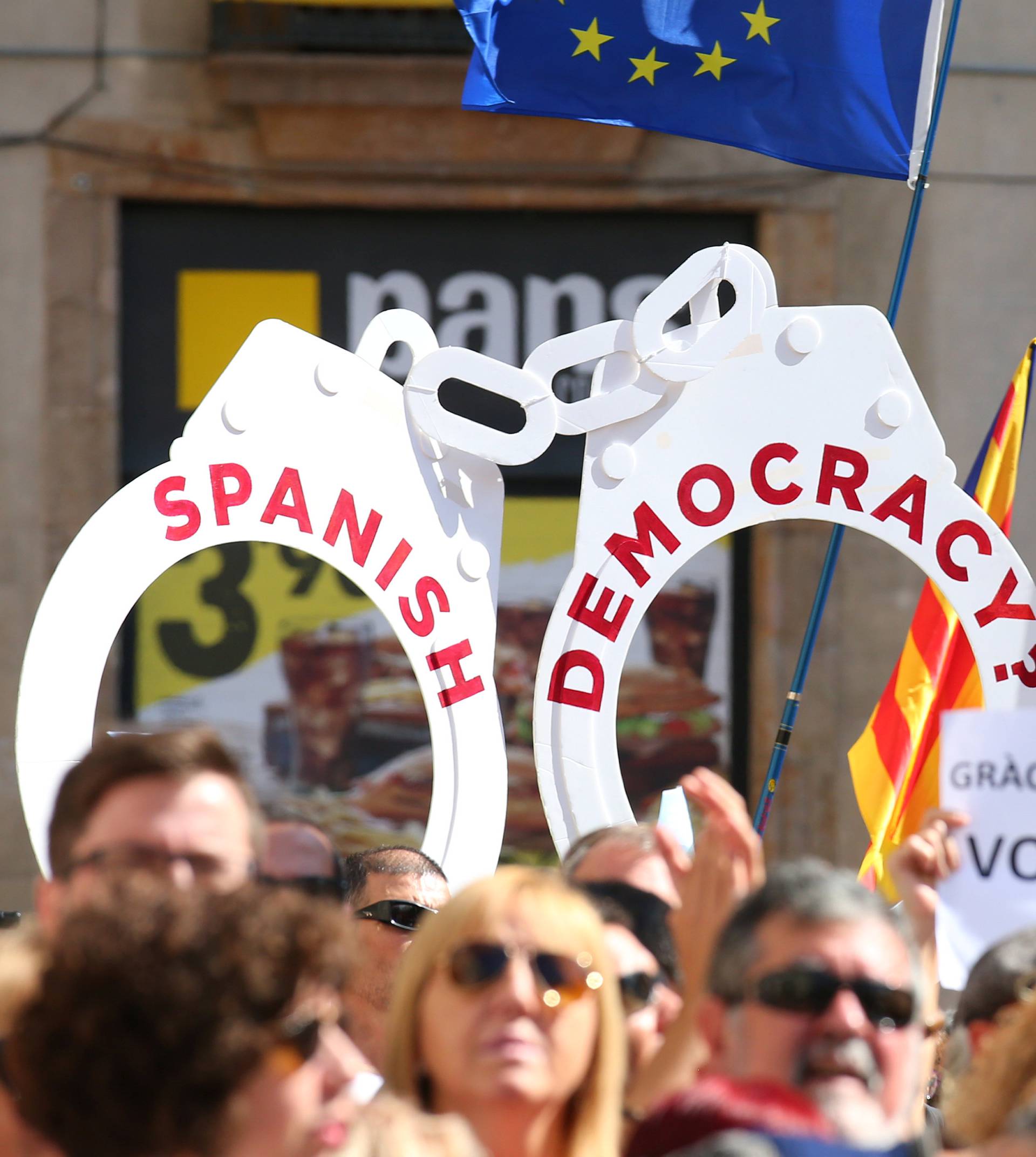 People raise up giant handcuffs and banners during the Catalan mayors protest in Barcelona