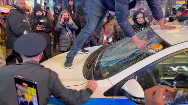 A protestor smashes the glass of a police car, at Times Square, in New York