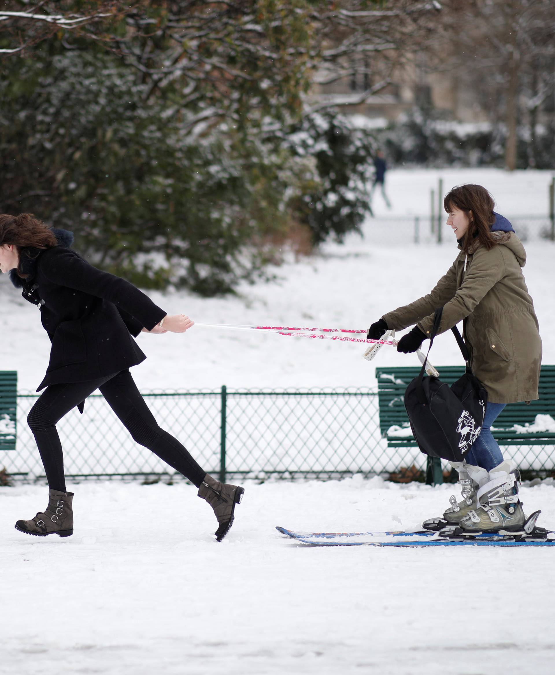 A young woman pulls another who uses skis in the Parc Monceau as winter weather bringing snow and freezing temperatures continues in Paris