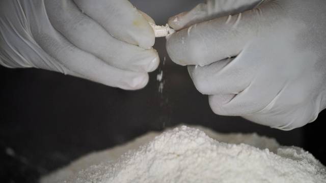 A Sinaloa Cartel member prepares methamphetamine capsules in a safe house in Mexico