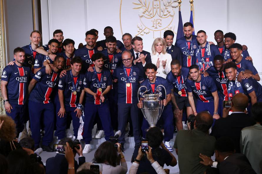 French President Emmanuel Macron and his wife Brigitte Macron, pose with the PSG team after the team won the Champions League, in Paris