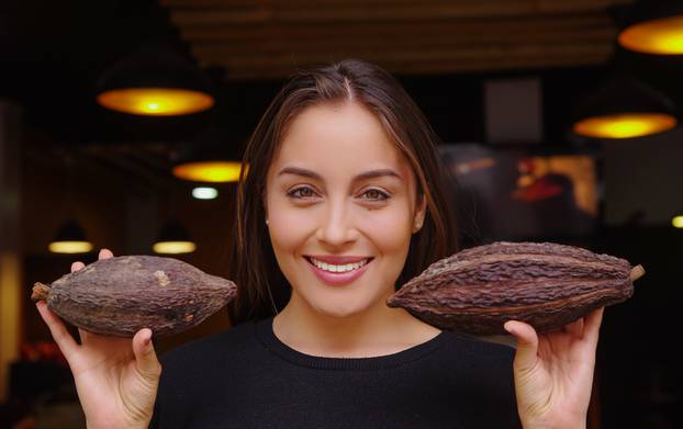 BANOS, ECUADOR, AUGUST, 17, 2018: Close up of beautiful woman holding in the hands two pieces of cacao pot and wearing black clothes