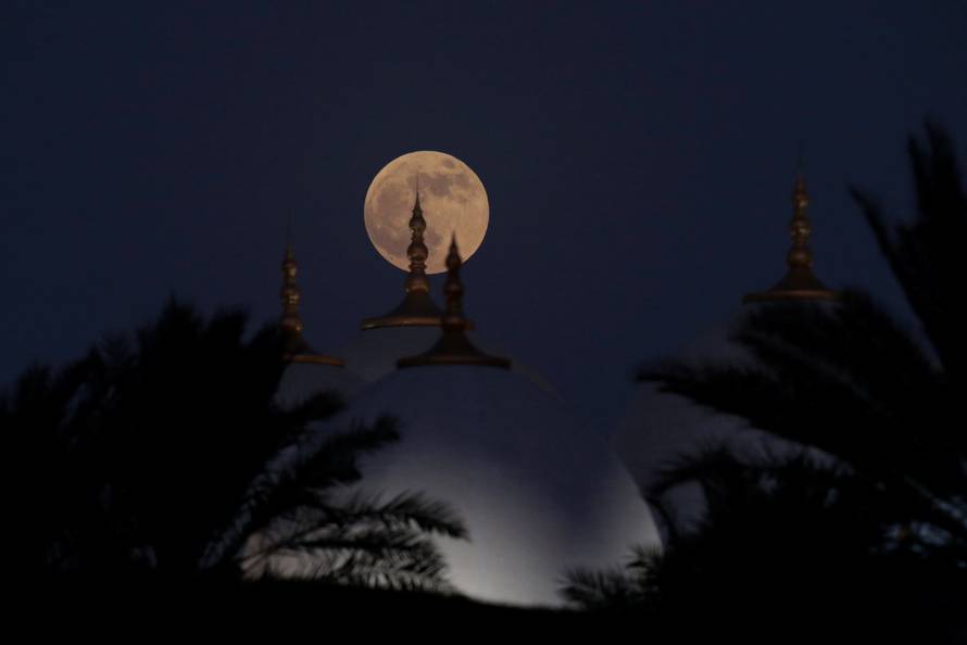 A lunar eclipse of a full "Blood Moon" rises behind the Sheikh Zayed Grand Mosque in Abu Dhabi