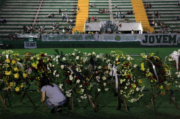 A woman places flowers before a mourning ceremony for victims after a plane carrying Brazil