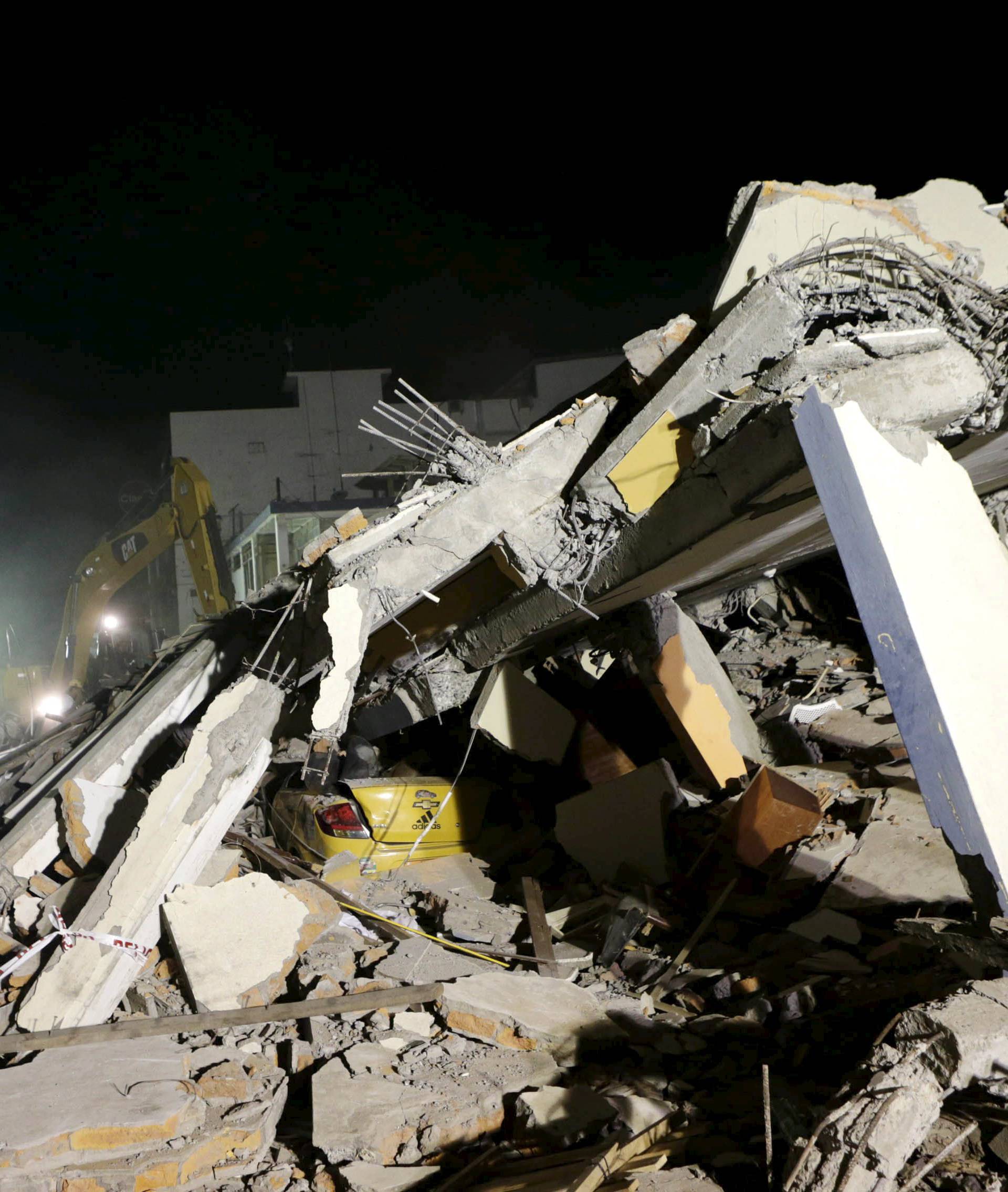 A flattened taxi is seen under the debris of a collapsed hotel in Portoviejo as heavy machinery works at the site after an earthquake struck off the Pacific coast in Ecuador