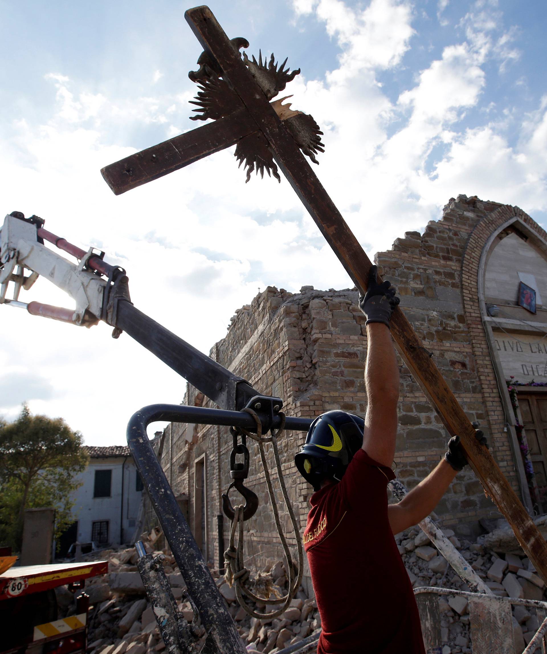 A firefighter carries away a crucifix from San Lorenzo e Flaviano church following an earthquake in San Lorenzo