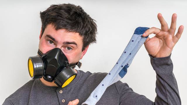 Man with gas mask is holding dirty stinky sock