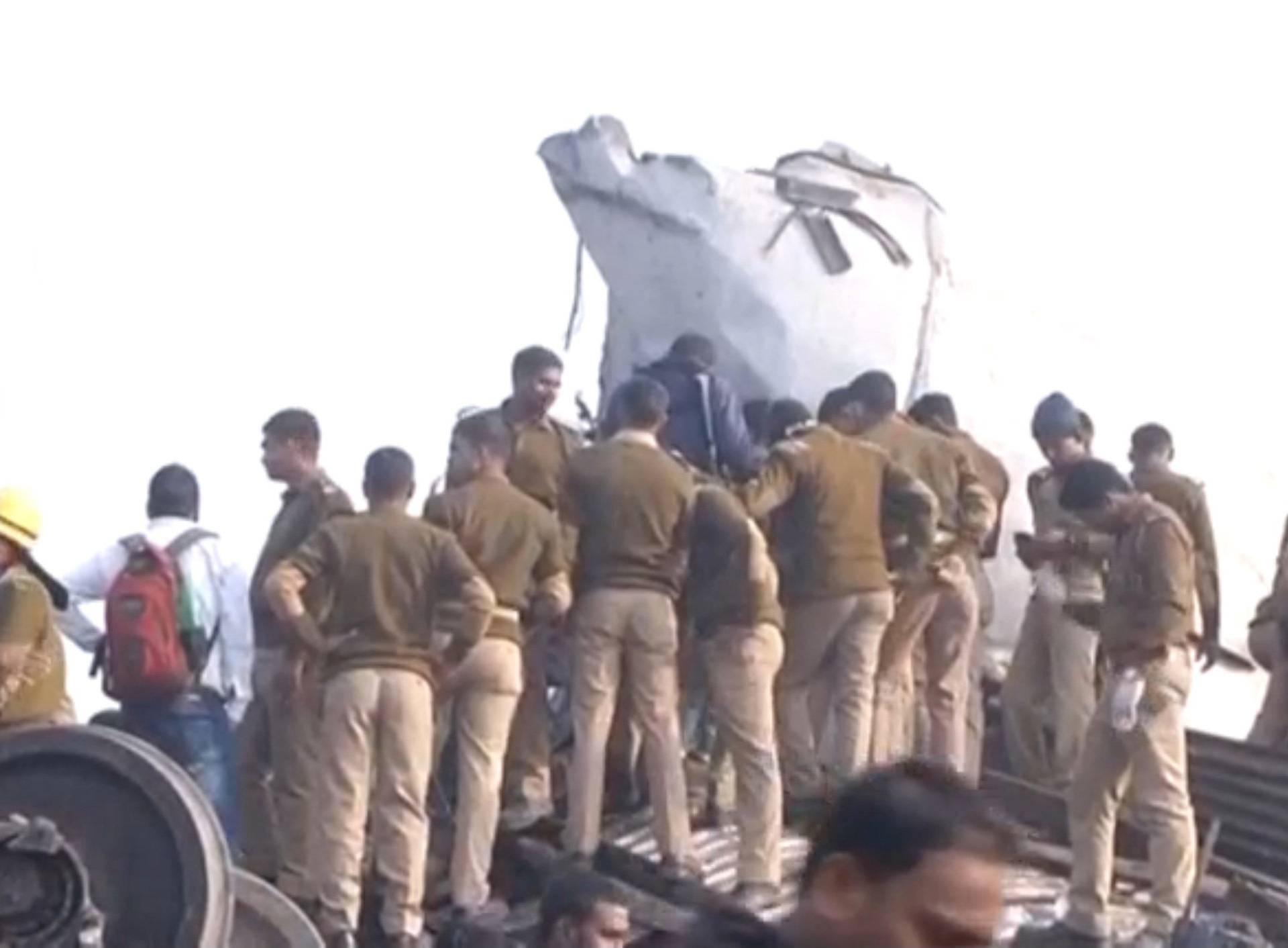 Police officers and people gather at the site where a train derailed in Kanpur, in India's northern state of Uttar Pradesh