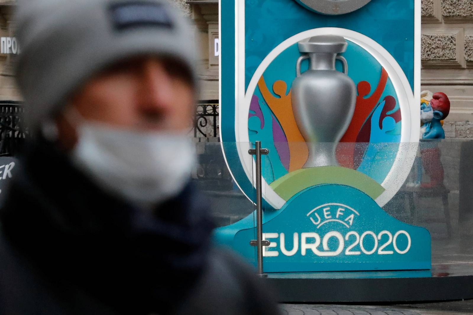 FILE PHOTO: A person wearing a protective face mask walks past the Euro 2020 countdown clock in Saint Petersburg