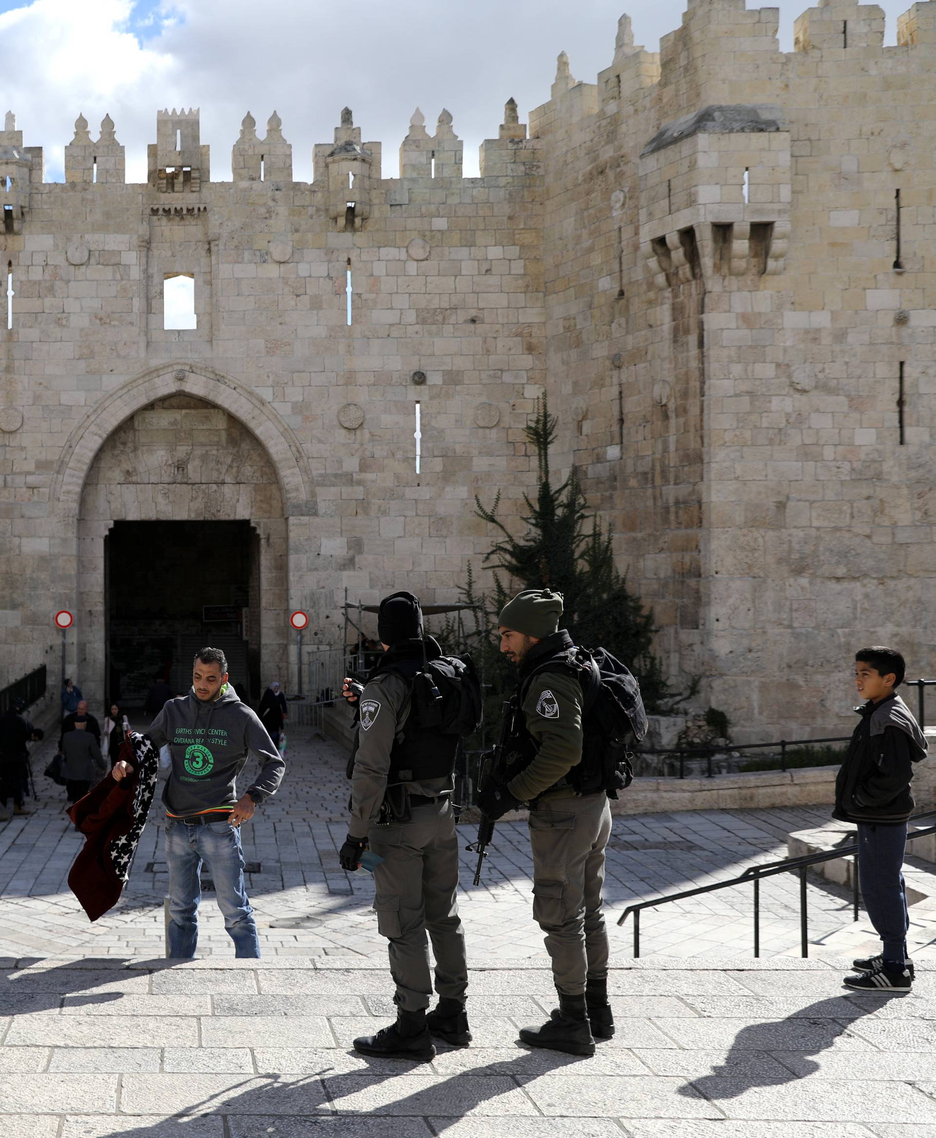 A Palestinian man removes his jacket during a security check by Israeli border policemen at Damascus Gate in Jerusalem's Old City