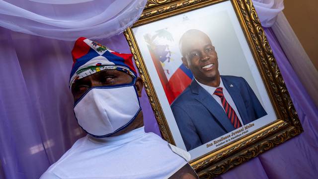 FILE PHOTO: A man stands next to a portrait of slain Haitian President Jovenel Moise placed on a memorial at the city hall in Cap-Haitien