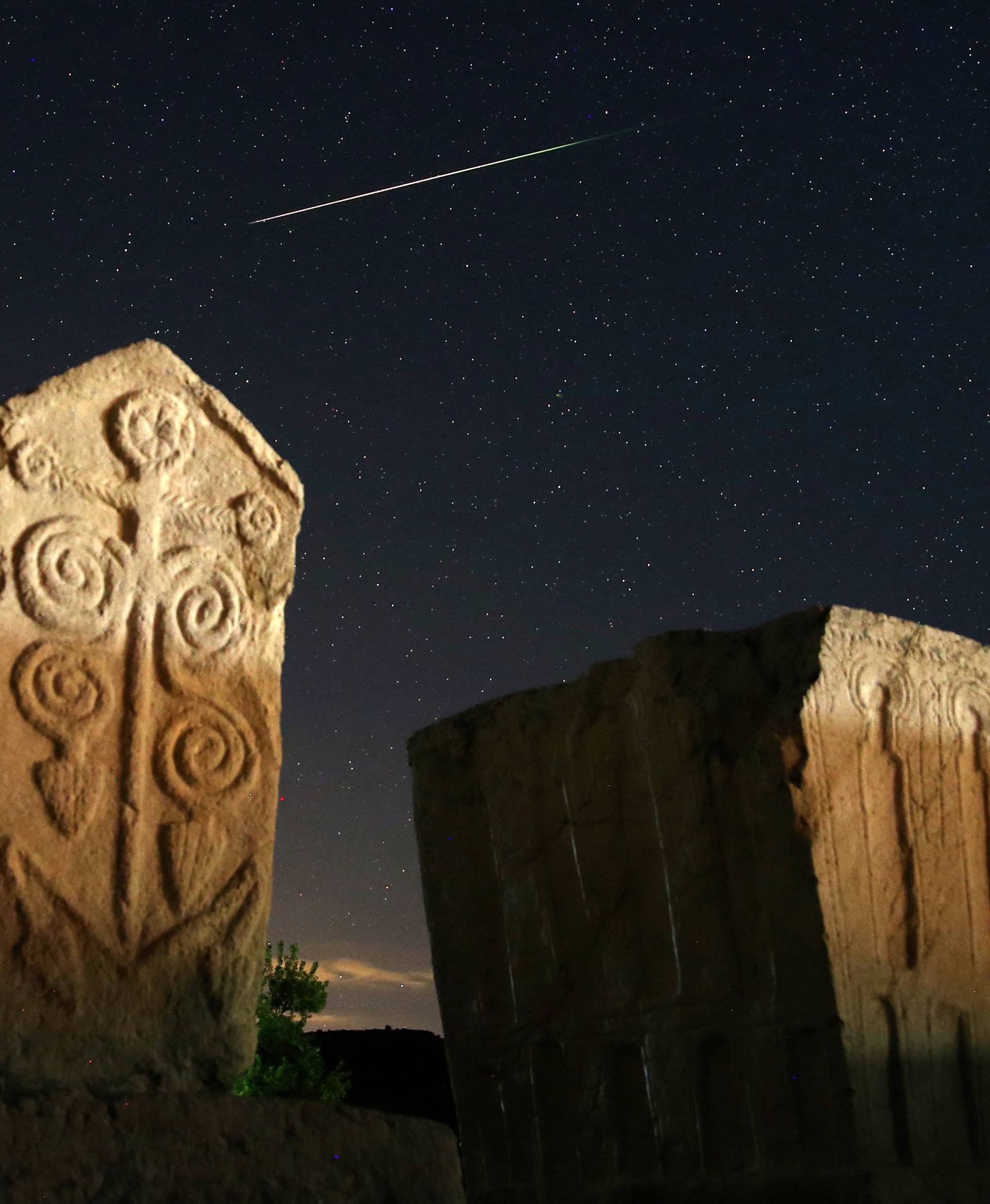 A meteor streaks past stars in the night sky above medieval tombstones in Radmilje near Stolac, south of Sarajevo