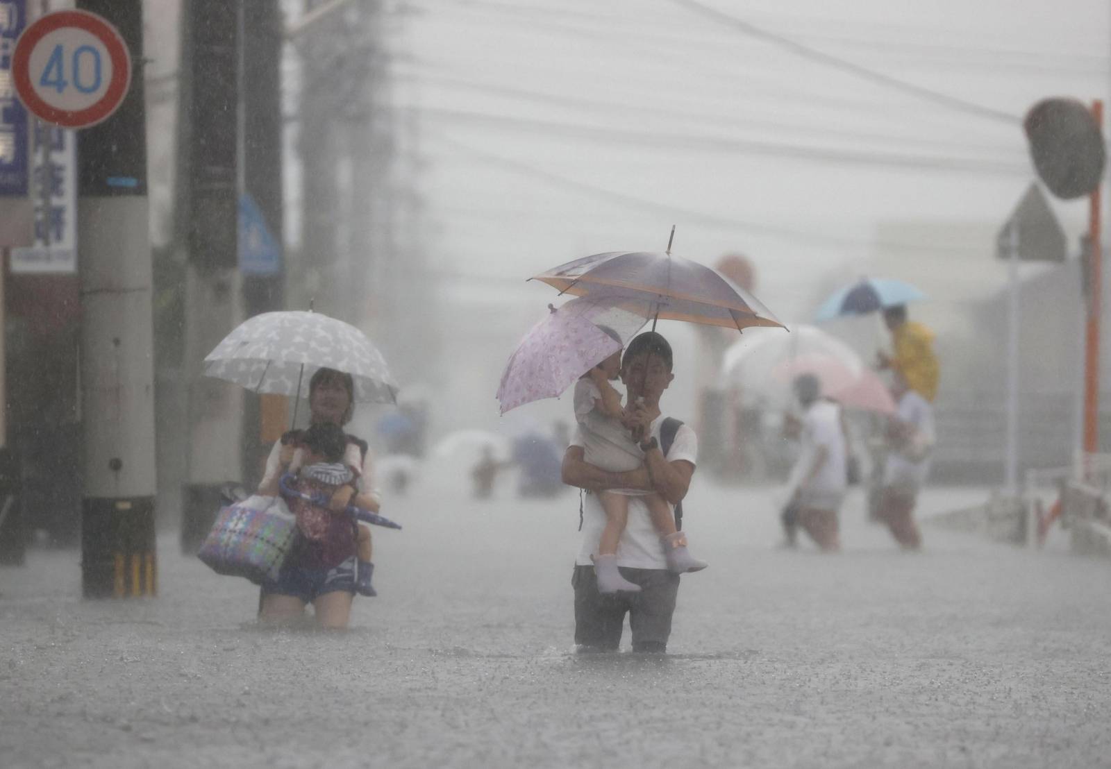 Local residents walk in a road flooded by heavy rain in Kurume, Japan
