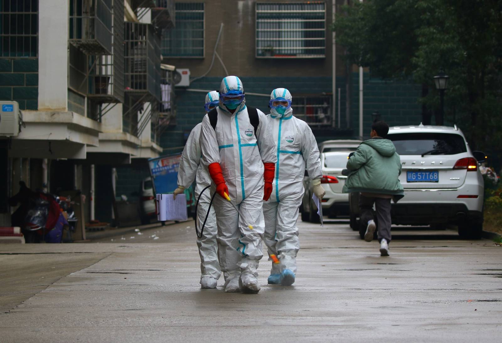 Workers from local disease control and prevention department in protective suits disinfect a residential area following the outbreak of a new coronavirus, in Ruichang, Jiangxi
