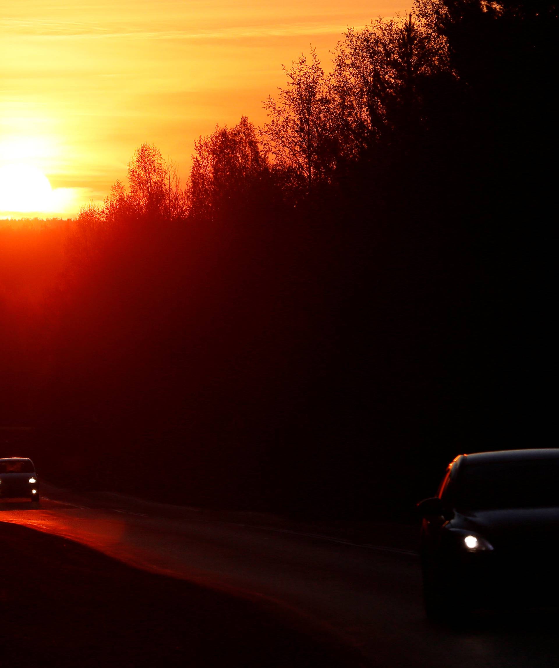 Vehicles drive along the M54 federal highway during sunset in the Taiga district south of Krasnoyarsk