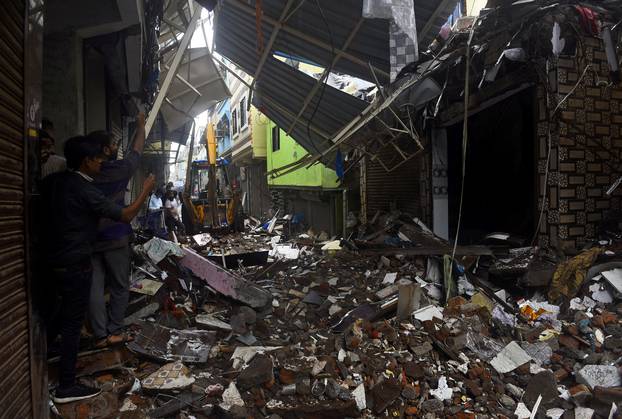 People use their mobile phones to take pictures of a collapsed building following rains in Mumbai
