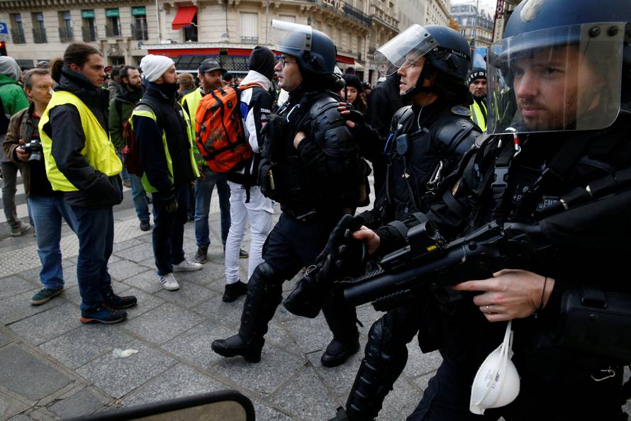Protesters wearing yellow vests stand in front of French Gendarmes during a national day of protest by the "yellow vests" movement in Paris