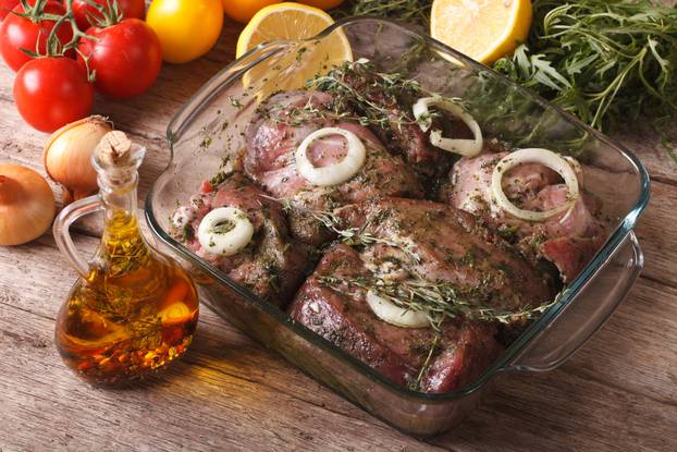 Meat marinated with onions, herbs and lemon close up. horizontal