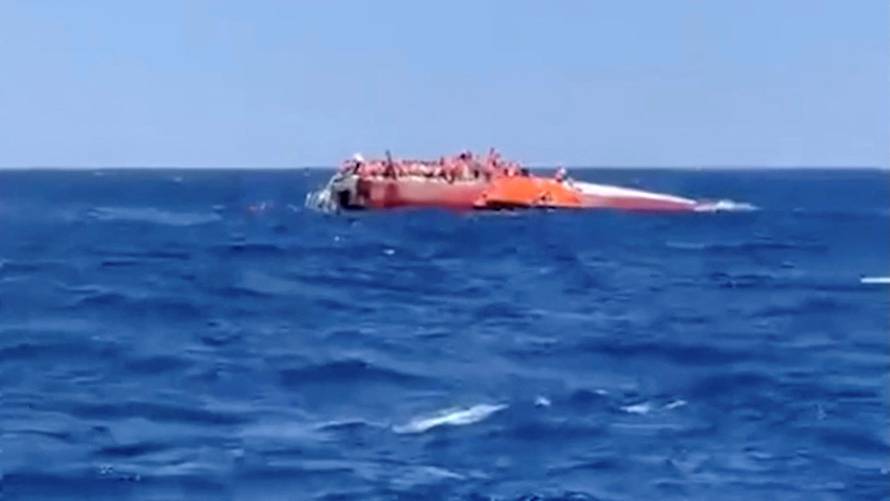 Passengers standing on the top of a capsized vessel off the coast of Northern Cyprus