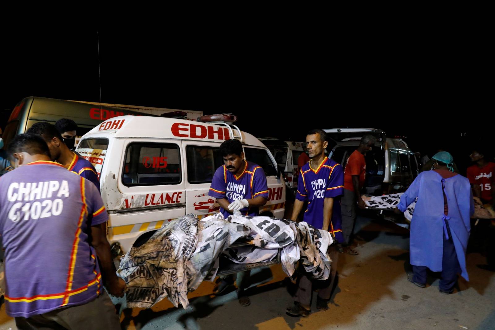 Rescue workers move bodies outside hospital morgue after a passenger plane crashed in a residential area near an airport in Karachi
