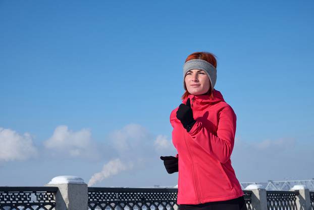 Running athlete woman sprinting during winter training outside in cold snow weather. Close up showing speed and movement