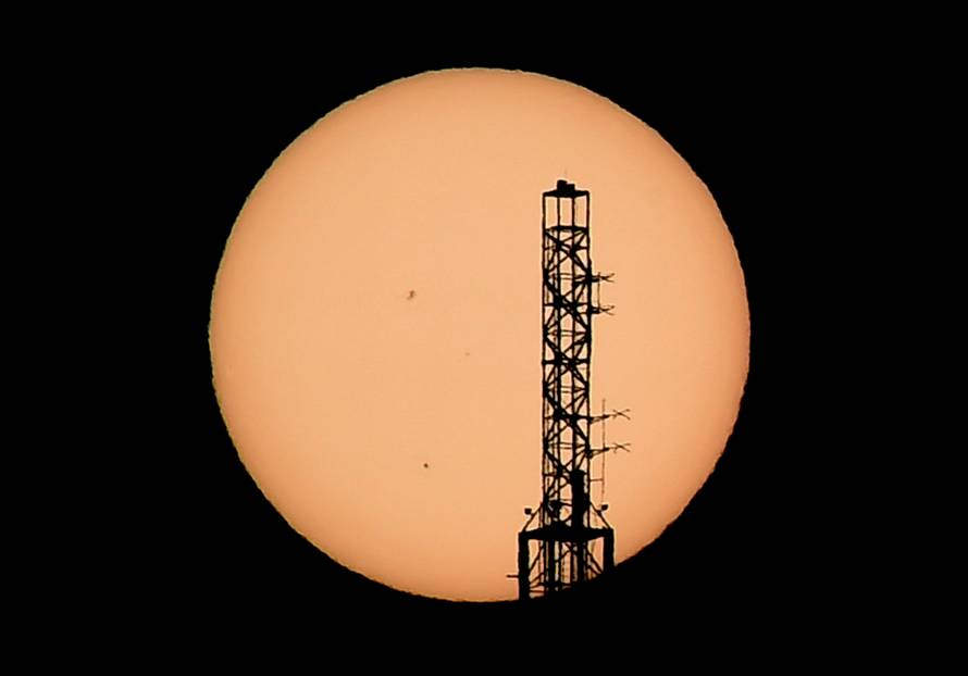 The top of the Stratosphere tower is silhouetted as the planet Mercury is seen, lower left quadrant, transiting across the face of the sun in Las Vegas