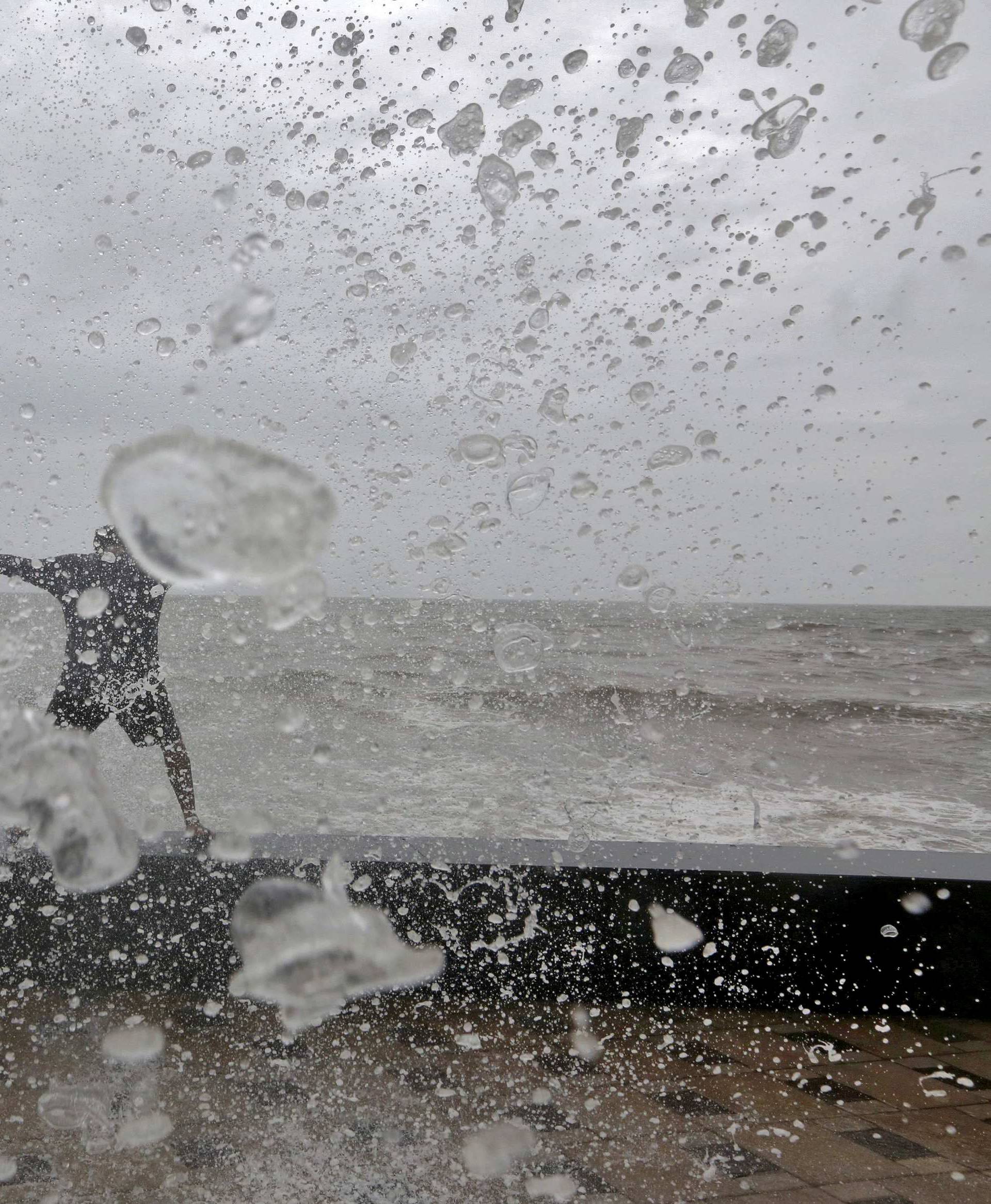 Boys get soaked by a large wave during high tide at the sea front in Mumbai