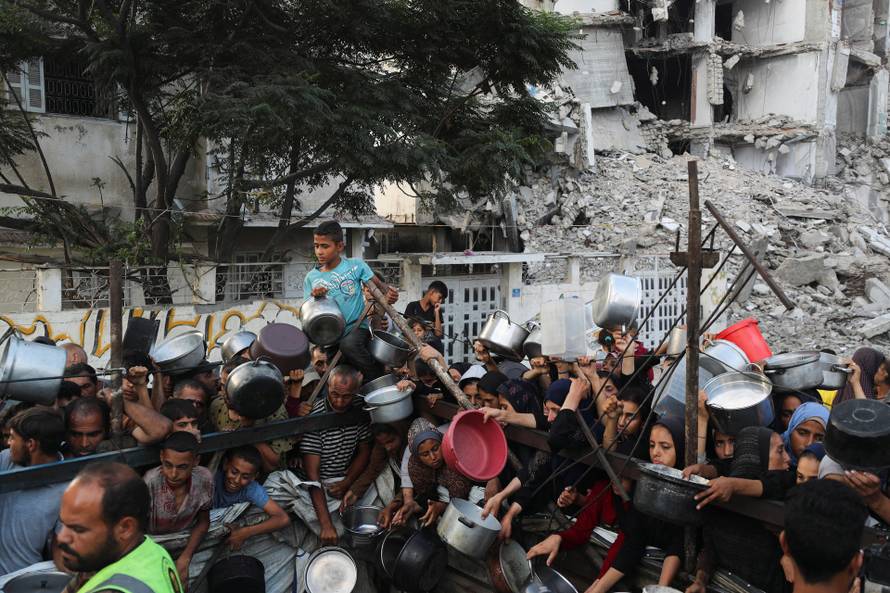 Palestinians wait to receive food from a charity kitchen, amid a hunger crisis, in Gaza City