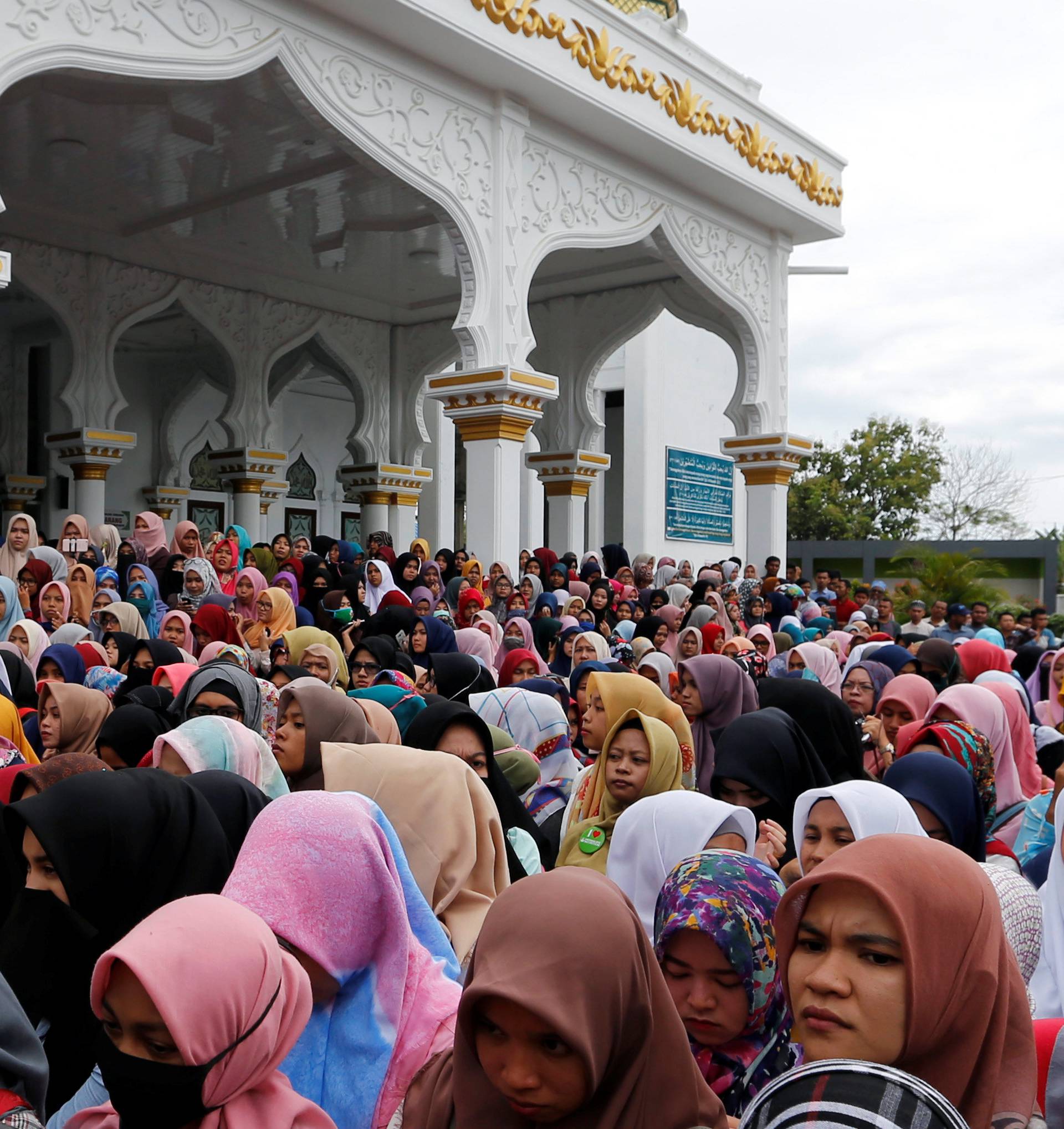 Indonesian women stand in front of the Syuhada mosque as they watch a man being publicly caned for having gay sex, in Banda Aceh