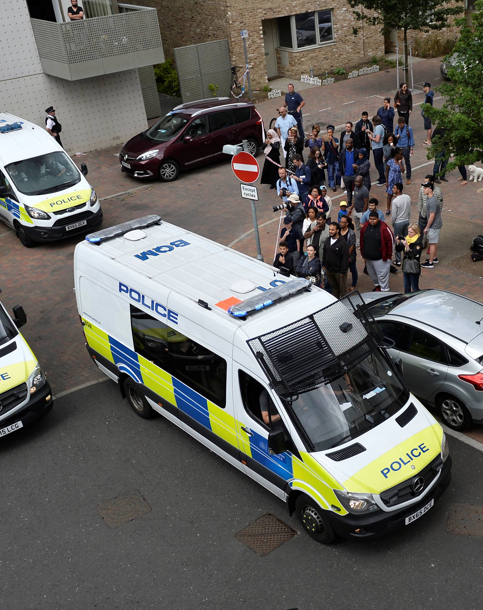 Police vans leave carrying a number of women who were detained after a block of flats was raided in Barking, east London