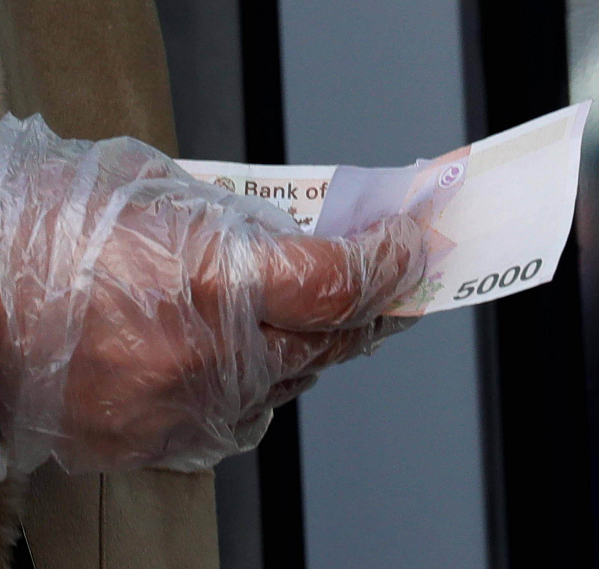 A woman wearing a plastic glove holds money as she stands in a queue to buy face masks amid the rise in confirmed cases of the novel coronavirus in Daegu