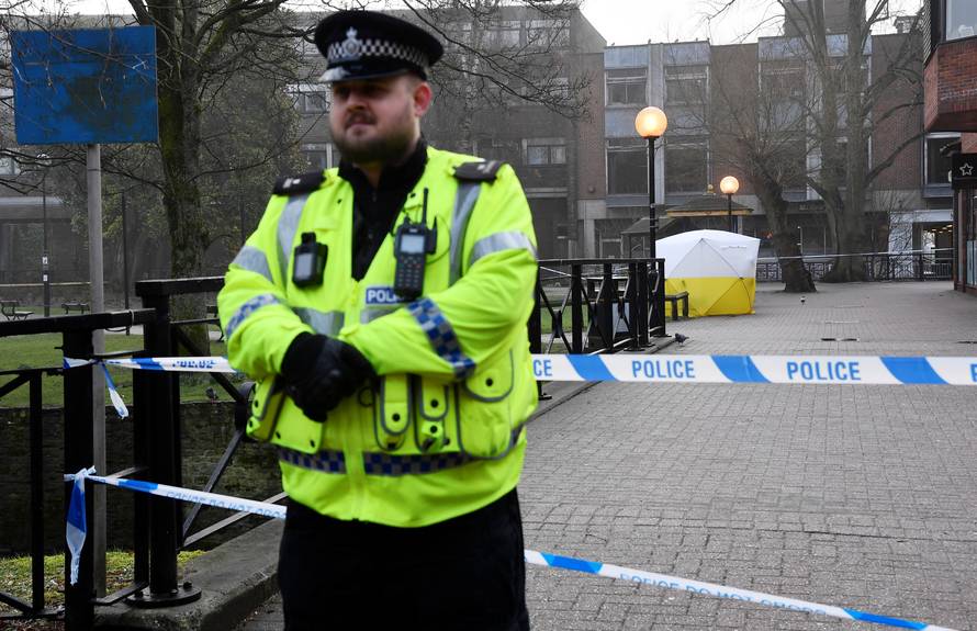 Police officers stand at crime scene tape, as a tent covers a park bench on which former Russian inteligence officer Sergei Skripal, and a woman were found unconscious after they had been exposed to an unknown substance, in Salisbury