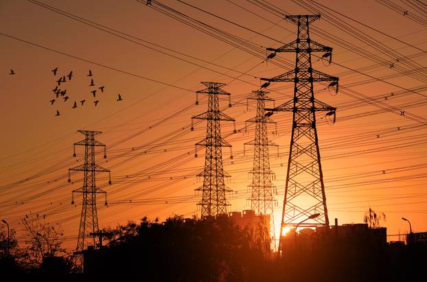 Electric,Power,Pylon,With,Flock,Birds,At,Sunset.