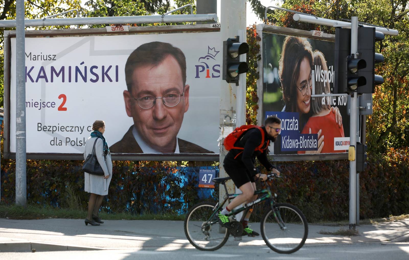 A woman walks in front of election banners in Warsaw